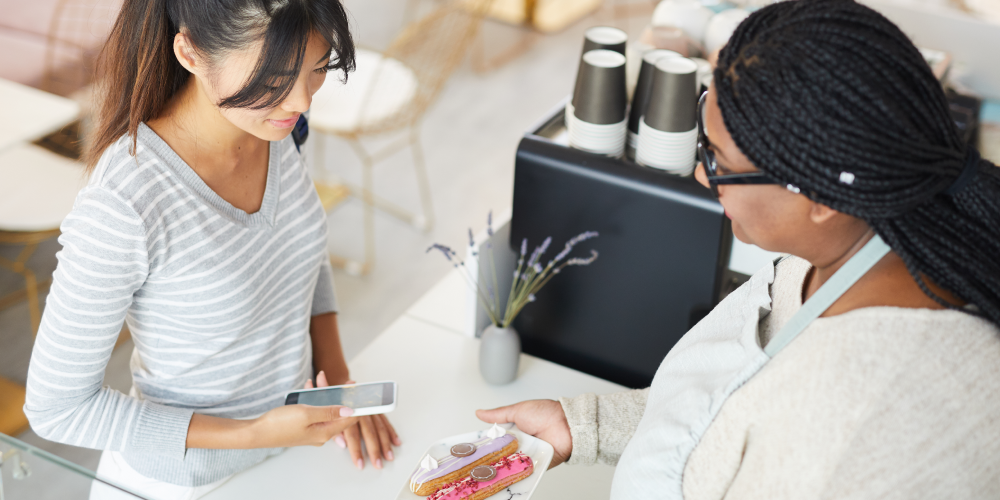 a women hold a mobile phone and ready to buy a cake in coffee shop